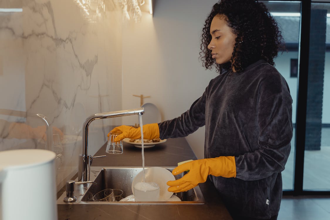 Woman in Black Long Sleeve Shirt Washing Dishes